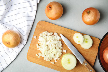 Flat lay composition with chopped and whole onions on grey table