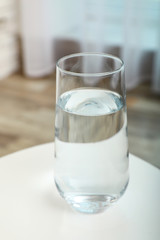 Glass of water on table in room. Refreshing drink