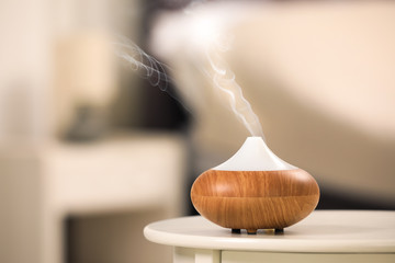 Modern essential oil diffuser on table indoors. Space for text