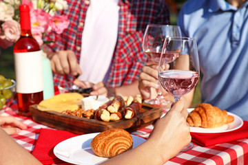 Group of people having picnic at table outdoors, closeup