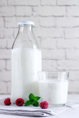 Organic probiotic milk kefir drink or yogurt in glass containers, with raspberry, on the white grey...