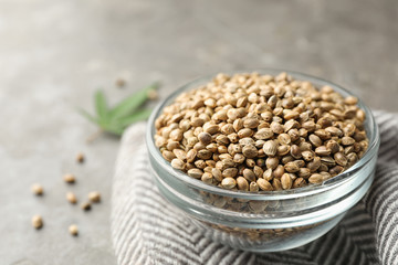Organic hemp seeds in bowl on grey table
