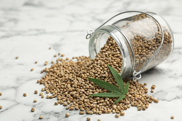 Organic hemp seeds and leaf on marble table