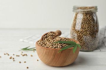Organic hemp seeds and leaf in bowl on white table