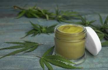 Obraz na płótnie Canvas Jar of hemp cream on blue wooden table, space for text. Organic cosmetics
