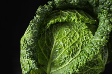 Fototapeta premium Fresh green savoy cabbage on black background, closeup