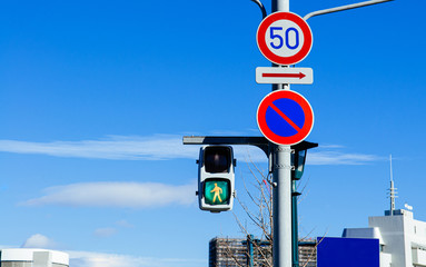 Street traffic light crosswalk sign against blue sky.