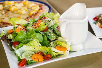 Close up view of  vegetable with sesame salad and a cup of dressing on food table