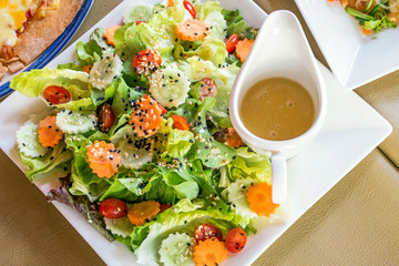 Top view of  vegetable with sesame salad and a cup of dressing on food table
