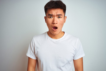Young asian chinese man wearing t-shirt standing over isolated white background afraid and shocked with surprise and amazed expression, fear and excited face.