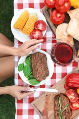 Woman eating steak at table outdoors, top view. Barbecue party