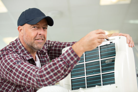 male technician cleaning air conditioner indoors