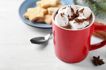 Composition of tasty cocoa with marshmallows in cup on white wooden table. Space for text