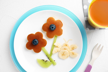 Fototapeta na wymiar Tasty pancakes served with blueberries, fruits and juice on white table, flat lay. Creative idea for kids breakfast
