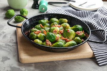 Tasty roasted Brussels sprouts with bacon on light grey table
