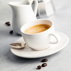 Coffee espresso in white cup with milk and coffee maker