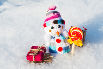 toy snowman with gifts and candy in the snow