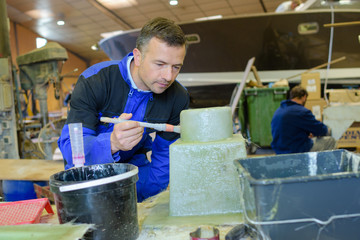boatmaker painting fibreglass structure in factory