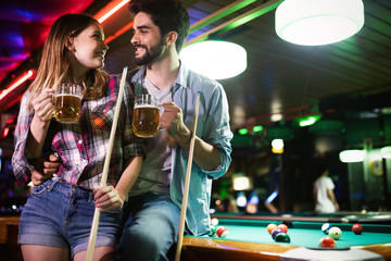 Happy young man playing snooker with his girlfriend. Happy loving couple.