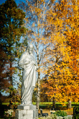 Naklejka premium Concrete statue of Jesus Christ painted with silver paint in cemetery