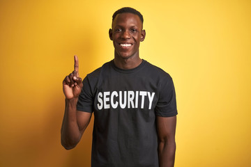 African american safeguard man wearing security uniform over isolated yellow background showing and...