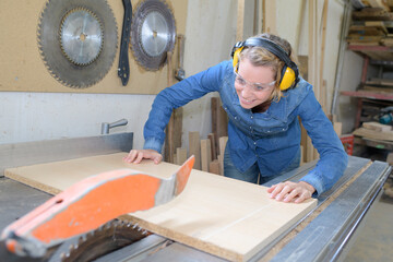 female carpenter cutting plywood using rotating saw