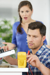 shocked woman looking at electrician technician measuring the voltage