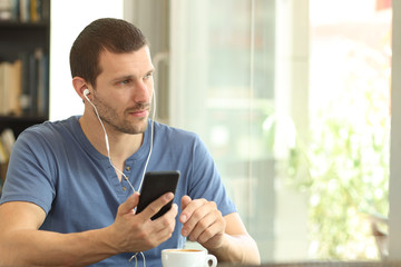 Relaxed adult man listening to music in a coffee shop