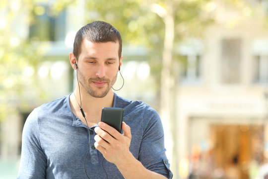 Adult Man Listening To Music Checking Cell Walking In The Street