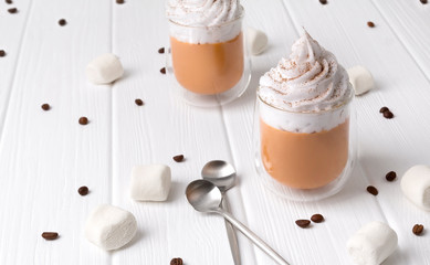 Pumpkin latte with whipped cream and spices on white wooden background.