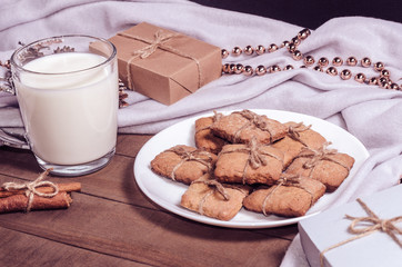 A cup of milk, cinnamon sticks and homemade cookies in a Christmas decor.