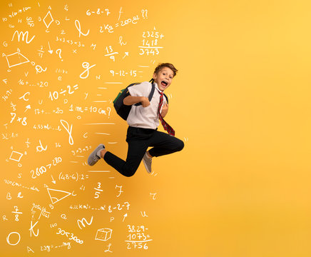 Young boy student runs fast to escape from school. Yellow background