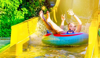 Boy having fun on yellow water slide at water park