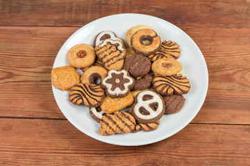 Different shortbread cookies on dish on rustic table