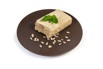 Piece of sunflower halva and sunflower seeds on brown dish