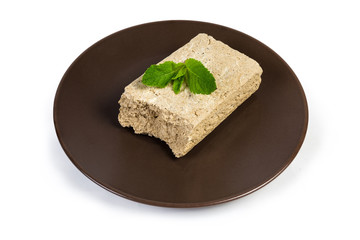 Piece of sunflower halva with mint leaves on brown dish