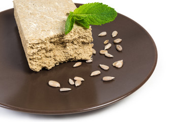 Piece of sunflower halva, sunflower seeds on dish close-up