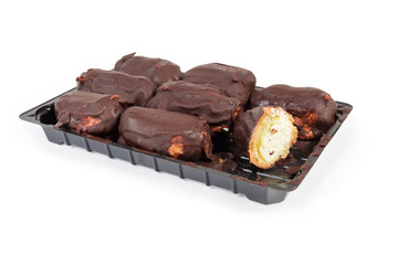 Eclairs with chocolate icing on plastic packaging on white background
