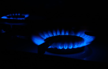 kitchen stovetop cook with blue flames propane gas burning, close-up