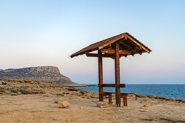 Romantic wooden bench overlooking the beautiful azure lagoon at sunset near Cape Greco. Cyprus.