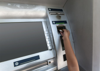 hand of a boy pokes a card at an ATM