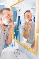 Guy shaving his beard in bathroom