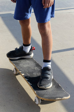 Feet of a kid who is standing on a skateboard in a skate park