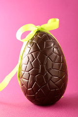 easter egg chocolate with bow on pink background