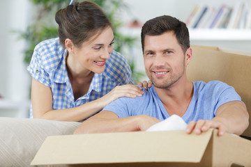 happy couple moving in new home unpacking boxes