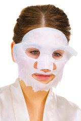 Woman applying sheet mask on face