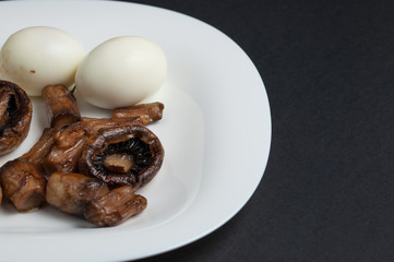 Mushrooms and boiled eggs on a white plate isolated on a black background.Natural food