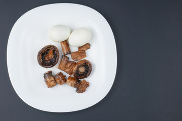 Fototapeta na wymiar Mushrooms and boiled eggs on a white plate isolated on a black background.Natural food