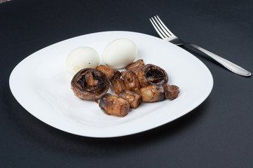 Mushrooms and boiled eggs on a white plate isolated on a black background.Natural food