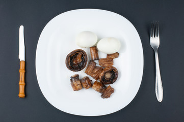 Mushrooms and boiled eggs on a white plate isolated on a black background.Natural food